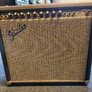 Kytarový kombozesilovač s černým potahem a béžovou textilní maskou. Na horním ovládacím panelu jsou nápisy Princeton 65, FENDER MUSICAL INSTRUMENTS a…