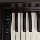 Detailní pohled na klávesnici digitálního piana s černým plastovým šasi. Vlevo se nachází ovládací panel s nápisy DEMO/SONG, PIANO/VOICE, METRONOME a…