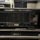 Zadní strana basového komba v černém provedení, umístěná v transportním case. Na spodním panelu je bílý nápis Ampeg Heritage SVT-410HLF. Na zadním pa…