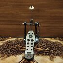 Fotografie zobrazuje jednoduchý pedál basového bubnu v černé a stříbrné barvě. Na šlapce je viditelný černý kruh s bílou číslicí 4 a v dolní části lo…