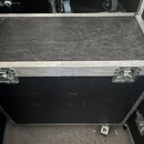 Černý transportní case s hliníkovými hranami a dvěma kovovými zámky v přední části. Povrch horní strany vykazuje viditelné škrábance a známky opotřeb…