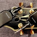 Na fotografii jsou dva černé bezdrátové vysílače s jack konektory, umístěné na hlavě elektrické kytary. Na levém zařízení je nápis RECEIVER a v dolní…