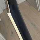 Detailní pohled na hranu černého trupu hudebního nástroje s krémovým lemováním. V místě spojení černého povrchu a světlého lemu je viditelná prasklin…