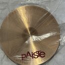 Kruhový mosazný činel v průhledném plastovém obalu. Na povrchu je v dolní části červený nápis pAiste a pod ním menší bílý text MADE IN SWITZERLAND. P…
