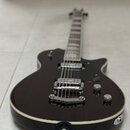 Tmavně hnědá elektrická kytara s jedním humbuckerem v pozici kobylky a černým pickguardem. Na pickguardu je viditelné zlaté logo s nápisem "Epiphone"…