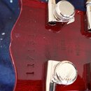 Detail zadní strany červené hlavy kytary s chromovanými ladičkami. Na povrchu je vyrazen nápis MADE IN USA 2013 MODEL a sériové číslo 11713151. Lak j…