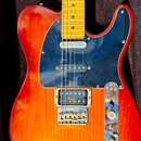 Elektrická kytara s tlemem v červeno-oranžovém sunburst provedení a hnědým javorovým hmatníkem. Nástroj má tmavě modrý pickguard, jeden krkový snímač…