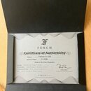 Fotografie znázorňuje certifikát pravosti v černém papírovém obalu. Na dokumentu je logo a nápis FURCH, nadpis Certificate of Authenticity a údaje Mo…