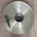 Kovový činel stříbrné barvy s viditelným kovánívým povrchem. Na levé straně je černý nápis Zildjian. V horní části plochy je viditelná prasklina směř…