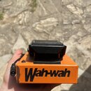 Oranžový efekt pedál typu wah-wah s černým gumovým pedálem. Na přední straně je černý nápis „Wah-wah“. Povrch krabice vykazuje známky opotřebení v po…