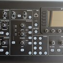 Černý digitální mixovací pult značky MIDAS. Zařízení obsahuje displej, řadu ovládacích knoflíků a tlačítek rozdělených do sekcí TALKBACK, MONITOR, CO…