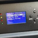 Detail ovládacího panelu světelného efektu s modrým LCD displejem a černým plastovým povrchem. Na displeji je text „Fixture Information“, „Fixture Us…