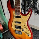 Elektrická kytara s trupem v červeno-žlutém sunburst provedení a hnědým hmatníkem. Nástroj má tři snímače (dvě jednosnívkové a jeden humbucker u koby…