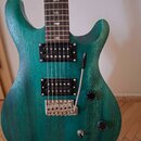 Elektrická kytara s tealovým povrchem s viditnou strukturou dřeva. Na hmatníku jsou v inlaids ve tvaru ptáků. Nástroj má dva humbuckery, Tremolo most…