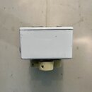 Bílý kovový box s hranatým tvarem. V dolní části jsou vidět dva světlé plastové oválné knoflíky s drážkami. Povrch boxu vykazuje drobné škrábance a n…