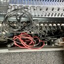 Černý mixovací pult značky PreSonus umístěný v transportním kufru. V zadní části jsou zapojeny zahlreiche kabelové konektory a v popředí leží smotané…