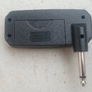 Černý plastový mini zesilovač s integrovaným 6,35mm jack konektorem. Na spodní straně je vyryt nápis „AMPLIFIER Battery AAX3 Made in China CE“. Povrc…