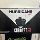 Fotografie znázorňuje kartónovou krabici s černobílým potiskem. Na krabici je uveden název HURRICANE 1000 a logo CHAUVET DJ. Uprostřed je vyobrazen č…