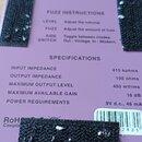 Záběr na zadní stranu fialového efekt pedálu. Je zde text „FUZZ INSTRUCTIONS“ s popisy ovládacích prvků LEVEL, FUZZ a SIDE SWITCH, dále tabulka „SPEC…