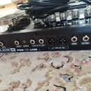 Fotografie zachycuje zadní panel černého kytarového procesoru s nápisem LINE 6 POD X3 LIVE. Jsou vidět různé konektory s popisky PEDAL 2, GUITAR IN,…