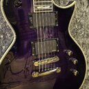 Elektrická kytara s fialovým průsvitným lakem a viditnou strukturou dřeva. Nástroj má dva humbuckery s nápisem EMG, jeden tónový potenciometr a jeden…