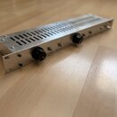 Stříbrné rackové zařízení z kovu s perforovaným horním krytem. Na předním panelu jsou dva černé oválné ovládací knoflíky a nápisy DISTANCE a RELEASE.…