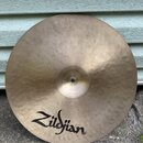 Kruhový mosazný činel s viditelným kovánívým povrchem. V dolní části je černý nápis Zildjian. Povrch vykazuje drobné škrábance a známky používání.