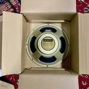 Kruhový reproduktor v kartonové krabici. Na středovém štítku je logo DELESTION a text: Model G12 NEO, Power capacity 50 watts, Impedance 8 ohms, Bass…