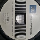 Fotografie zachycuje zadní část reproduktoru s bílým štítkem. Na štítku je modré logo JBL a nápis Musical Products. Dále jsou zde texty MODEL E120-16…