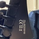 Záběr na zadní stranu černé hlavy elektrické kytary s ladicími kolíky. Na povrchu je bílý nápis SERIAL NUMBER IW2103030100, MADE IN INDONESIA a značk…