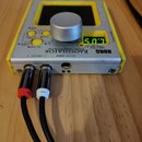 Žlutý syntetizátor KORG KAOSSILATOR s hliníkovým šasi a stříbrným ovládacím knoflíkem. Na přístroji je nápis DYNAMIC PHRASE SYNTHESIZER a digitální d…