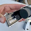 Fotografie zachycuje spodní část černého bubnového triggeru s chromovanými prvky. Na černé ploše je bílé logo YAMAHA a nápis DT50K. Pod ním se nacház…