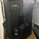 Černý aktivní reproduktor z plastového materiálu s integrovanou rukojetí na zadní straně. V horní části je ovládací panel s displejem, několika otočn…