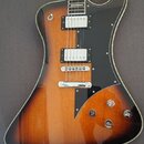 Elektrická kytara s korpusem v barevném přechodu od žluté přes oranžovou k tmavě hnědé. Nástroj má černý plech, dva humbuckery s bílými kryty a chrom…