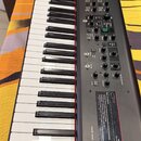 Černý digitální stage piano s bílými a černými klávesami. Na pravé straně se nachází ovládací panel s řadou tlačítek, posuvníků a otočných knoflíků.…