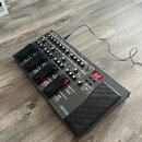 Šedý efektový pedál s černými spínači a expresním pedálem. Na horní části je nápis BOSS ME-80 guitar multi-effects processor a v pravé části svítí če…