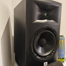 Černý studiový monitor s hornovým výstupem pro vysoké frekvence a kulatým basovým reproduktorem. V dolní části je viditelné bílé logo JBL. Reprodukto…