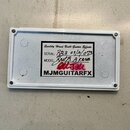Zadní strana bílého efekt pedálu v kovovém šasi. Uprostřed je nalepený štítek s nápisy „Quality Hand Built Guitar Effects“, „SERIAL: BB3 01/1/023“, „…