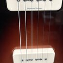 Detail elektrické kytary s hnědým průhledným lakem a dvěma krémovými snímači. Na obou snímačích je viditelný nápis Seymour Duncan. V dolní části je k…