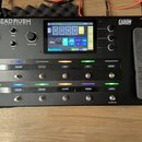 Černý kytarový procesor HeadRush Pedalboard s displejem a ovládacími prvky. Na horní části je nápis HEADRUSH PEDALBOARD a vpravo logo POWERED BY Elev…