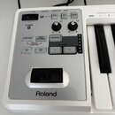 Detail ovládací sekce bílé klávesové nástroje značky Roland. Panel obsahuje několik tlačítek s nápisy FUNCTION, Super NATURAL, TRANSPOSE, VISUAL CONT…