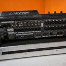 Zadní strana černého digitálního mixážního pultu značky behringer, umístěného v transportním kufru. Na zařízení je vidět nápis X32 COMPACT a označení…