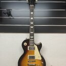 Elektrická kytara s trupem v barvě sunburst a krčkem z tmavého dřeva. Na hlavě je bílý nápis Epiphone a podpis Les Paul. Nástroj má dva humbuckery, č…