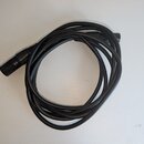 Černý audio kabel svinitý do kruhu. Na koncích jsou černé konektory, z nichž jeden je viditelný v celku. Na povrchu kabelu je nečitelný nápis.