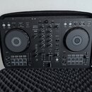 Černý DJ kontrolér Pioneer DJ model DDJ-FLX4 umístěný v černé polstrované přepravní brašně. Na přístroji jsou viditelné nápisy rekordbox a serato. Po…