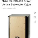 Fotografie zobrazuje vertikální cajon v černo-přirozené dřevěné kombinaci. Přední dopadová plocha je zC světlého dřeva s černým logem MEINL. Boční st…