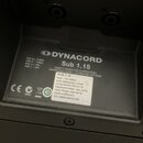 Fotografie zachycuje zadní část černého subwooferu s viditelným štítkem. Na štítku je logo a nápis DYNACORD, model Sub 1.15 a popis DIRECT-RADIATING…