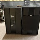 Dvě černé basové reproducing s hranatým tvarem. Na levém je vidět logo HK a nápis LINEAR SUB 1200. Pravý reproduktor je překryt černým textilním kryt…