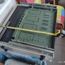 Kovový rackový rám s vloženým zeleným kovovým panelem, na kterém jsou ručně nakreslené obdélníky s čísly 5, 6, 4 a 8. Přes panel je natažený žlutýv m…