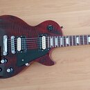 Elektrická kytara s tmavě červeným plamenovitým povrchem korpusu. Nástroj má dva humbuckery s krémovými kryty snímačů, Tune-o-matic kobylku a čtyři o…